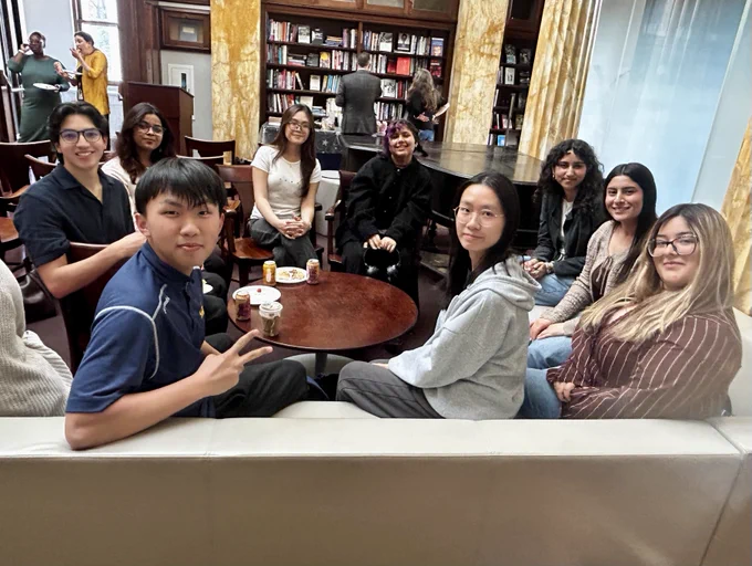 A group of students sitting around a table, smiling at the camera.