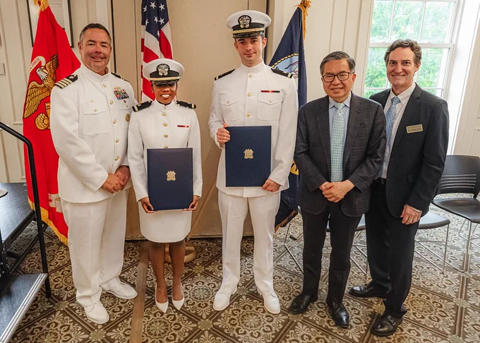 Three people dressed in white naval uniforms (Captain Dennis Farrell and graduating students Dana Clarke and Paul Randall) and two people dressed in dark suits and ties (Dean Shih-Fu Chang and Vice Dean Barclay Morrison) smile and pose for the camera at the NROTC commissioning ceremony at Columbia University Faculty House.