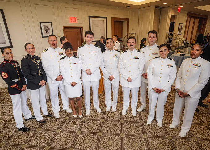 Ten people including Dana Clarke Paul Randall in naval uniforms smile and pose for the camera at the NROTC commissioning ceremony at Columbia University Faculty House.