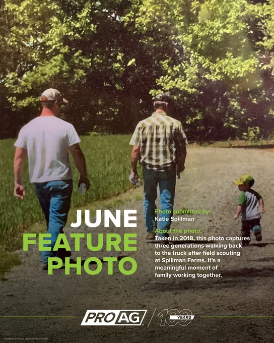 Two adults and young child are walking on a dirt path surrounded by greenery at Spillman Farms. The text on the image reads: "JUNE FEATURE PHOTO - Taken in 2018, this photo captures three generations walking back to the truck after field scouting. It's a meaningful moment of a family working together." The bottom includes logos for ProAg crop insurance company and a 100-year celebration. ProAg is an equal opportunity provider. 