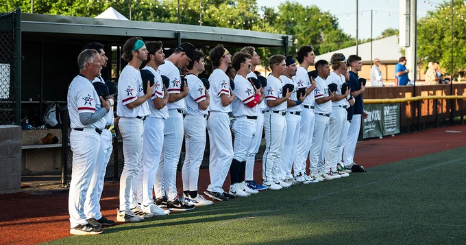 Yard Dogs players and staff stand for the National Anthem, holding their hats over their hearts.