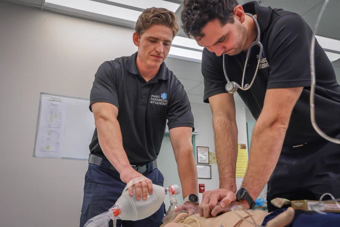 Two male PHSC students performing CPR on practice dummy.