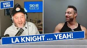 Two people are in a split-screen video call. The person on the left is speaking into a microphone with the "Mackey & Judd" logo in view, while the person on the right is smiling. The text on the screen reads "LA KNIGHT ... YEAH!