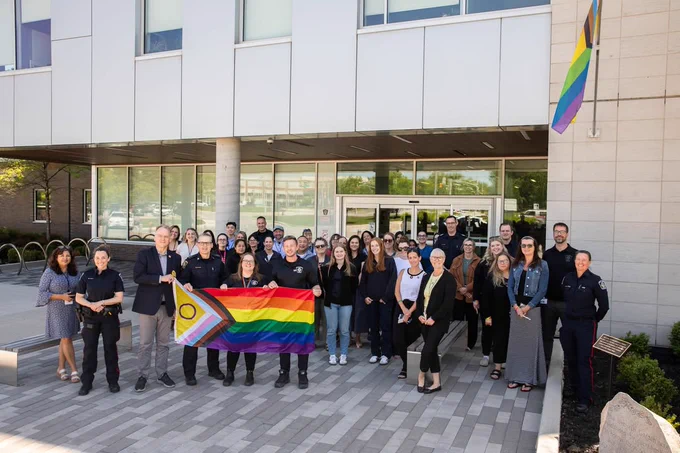 Members of the HRPS in front of headquarters holding the pride flag.