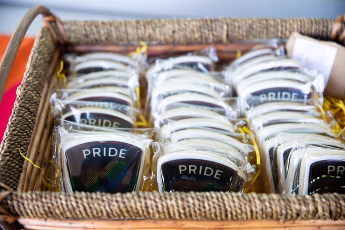 Individually wrapped police badge shaped cookies in a basket reading "PRIDE" with a rainbow heart made of fingerprints.