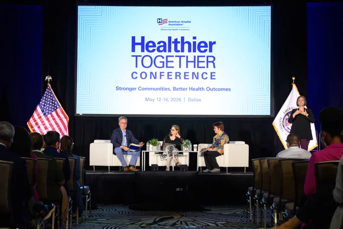 [Image 1: Sam Crane, Michelle A. Meade & discussion moderator Andrew Jager sit on a stage below a screen that says, “American Hospital Association Healthier Together Conference. Stronger Communities. Better Health Outcomes. May 12 - 14, 2026. Dallas.” An audience sits in front of them, & a sign language interpreter stands to the side of the stage.]