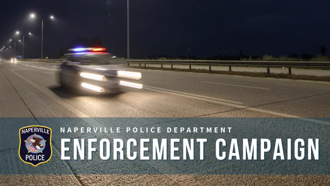 Naperville police car speeding on a highway at night with flashing red and blue lights during enforcement campaign.
