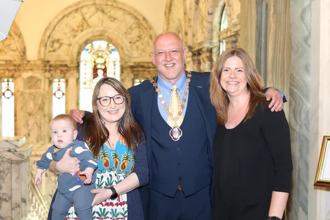 Cllr Hedley Abernethy at top of inside Belfast City Hall staircase with fellow Ormiston Councillors Christine Bower and Jenna Maghie, all smiling.