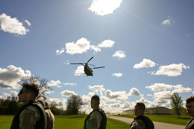 Soldiers walking past hovering Chinook.