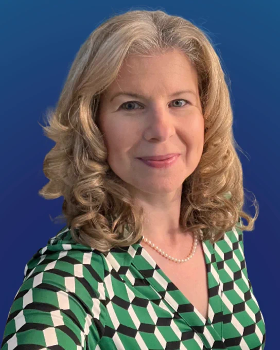 A person smiling against a blue background. They are wearing a green business casual shirt.