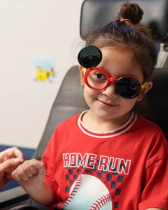 Child wearing occluder glasses in eye exam chair. 