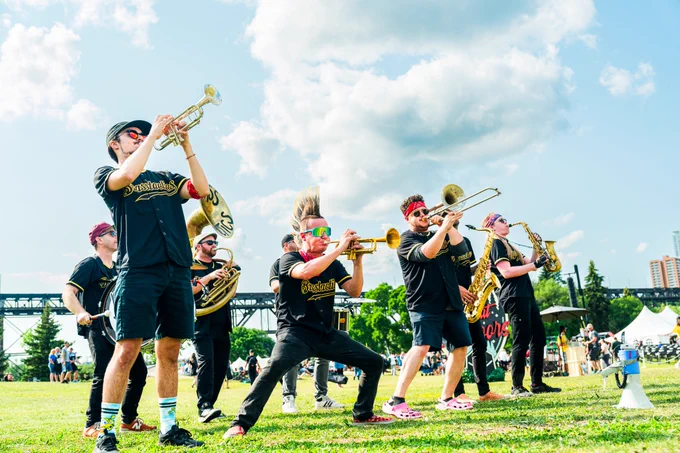A group of individuals in matching outfits playing a variety of musical instruments in the park. 