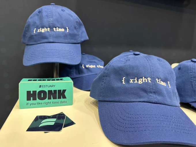 Blue baseball caps displayed on a table, each with the text "{ right time }" embroidered on them. Nearby, a small teal sticker that says "HONK if you like right time data".