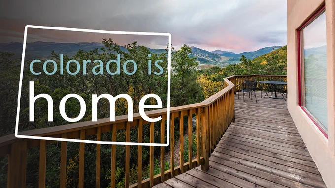 Photo of an upper-story deck overlooking a mountain view with the words "colorado is home" surrounded by a border in the shape of Colorado.