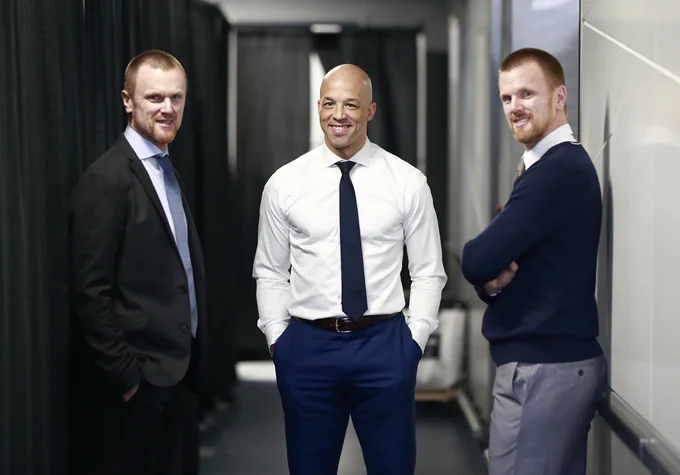 Henrik Sedin, Manny Malhotra and Daniel Sedin smiling together for a photo. 