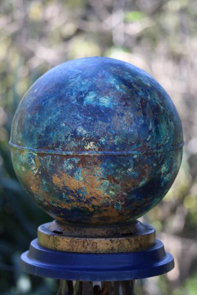 A garden globe colored with splattered blue and gold paint