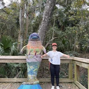 A picture of Duanya Lyu with a sculpture of a manatee.