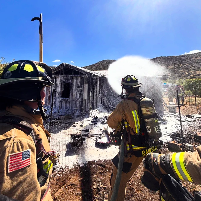 Three firefighters fight a structure fire.