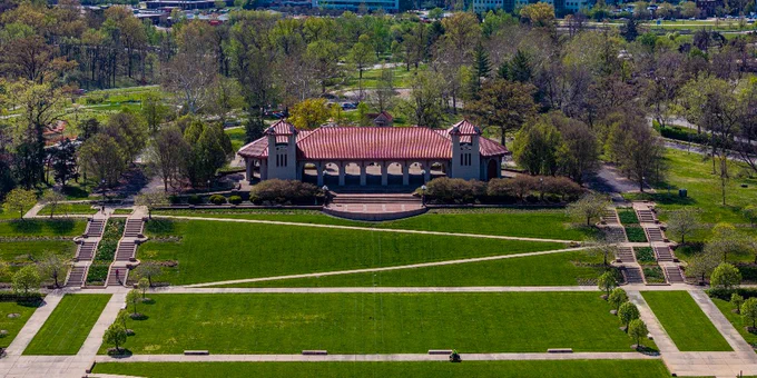 An aerial centers the World's Fair Pavilion as sidewalks zigzag through Government Hill in the foreground while spring trees bud behind the structure. 