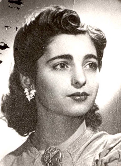 Vintage black-and-white portrait of a young woman with wavy hair, wearing earrings and a floral dress. 