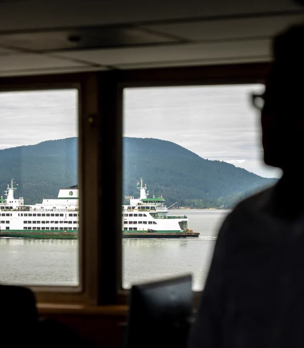 Bob on right in bridge of ferry, another ferry outside the window on the left