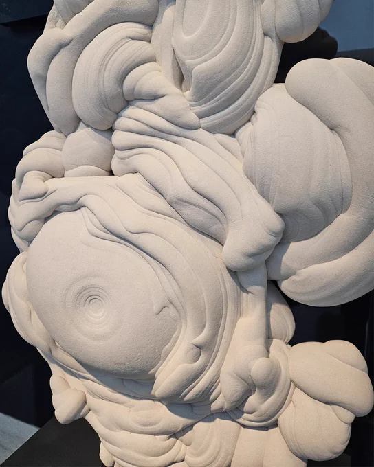 A close up of a large white sandstone sculpture, with multiple grooves and indents. 