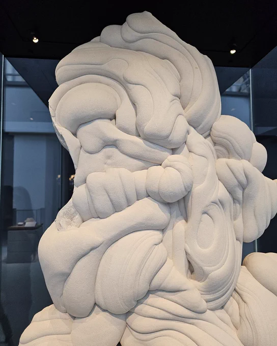 A close up of a large white sandstone sculpture, with multiple grooves and indents. 
