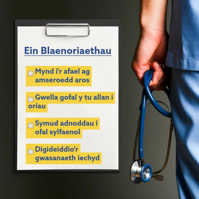 Clipboard listing NHS priorities including tackling waiting times and digitisation, held next to a healthcare worker in blue scrubs with a stethoscope.