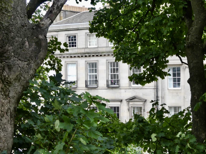 New Town building glimpsed through foliage.