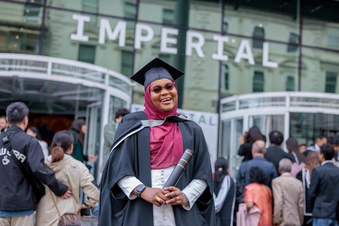 Graduate standing outside of the main entrance