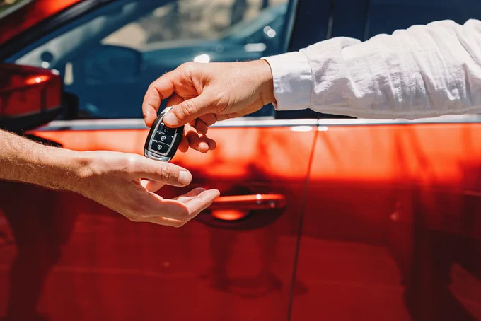 person handing another person car keys