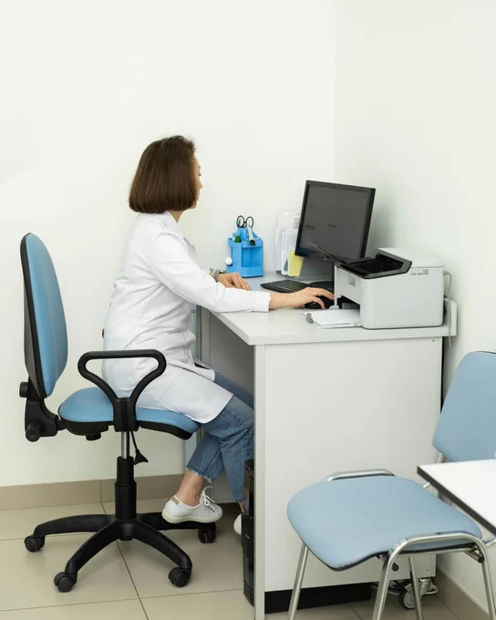 Healthcare professional using a computer in a hospital office, illustrating the digital exchange of oncology patient data and improved coordination of cancer care in Latvia