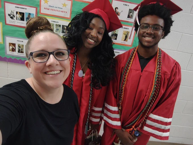 Music Teacher and 2 graduates in red cap and gown