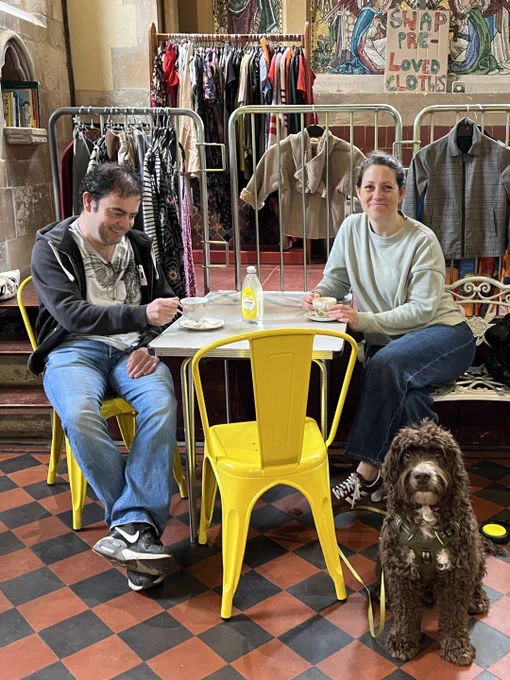 A man and a woman sitting inside The Fixery, accompanied by their dog