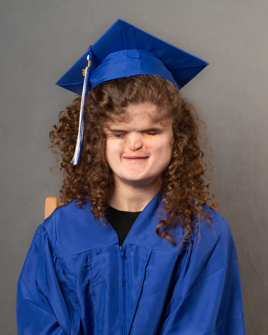 Madilyn smiling at the camera, wearing a blue cap and gown