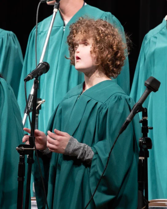Madilyn performing in a choir concert, wearing a green gown
