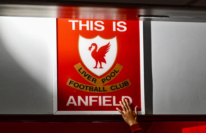 A Liverpool player touches the iconic 'This Is Anfield' sign on the way out to the pitch.