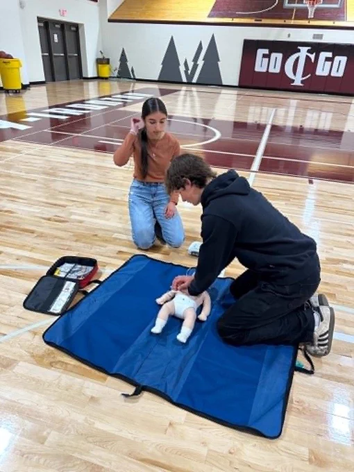 male student performing CPR on an infant manaquin
