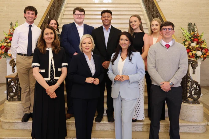Image of 10 people - including First Minister Michelle O’Neill and deputy First Minister Emma Little-Pengelly - standing in front of steps in Great Hall at Parliament Buildings.