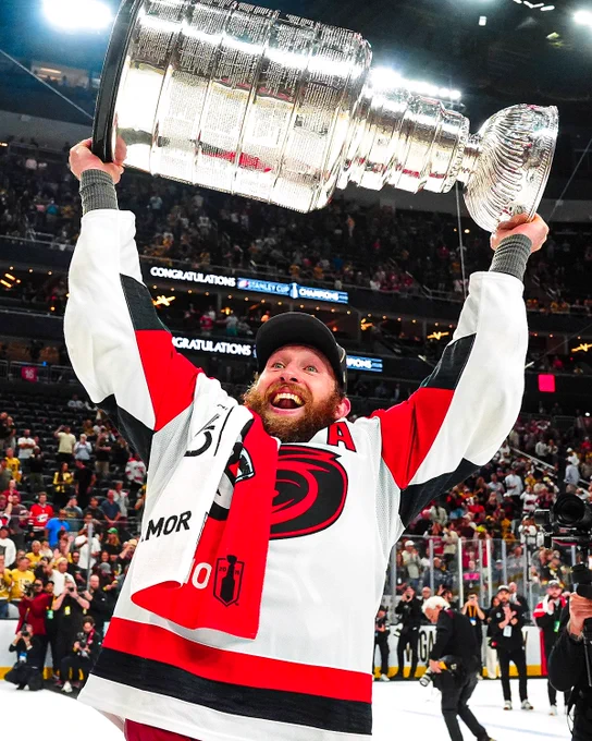 Jaccob Slavin lifts the Stanley Cup on ice in a Hurricanes uniform. 