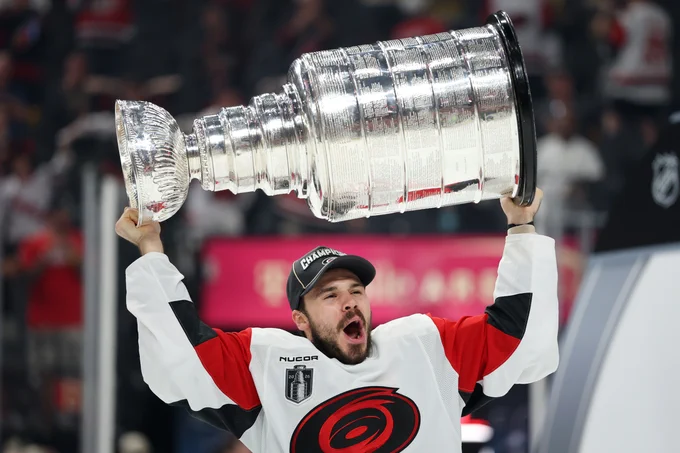 Logan Stankoven hoisting the Stanley Cup in a Hurricanes uniform.