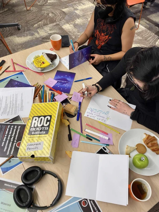Image description: Picture of people writing cards at the Pōneke 2026 Matariki Holiday Card Drive. 