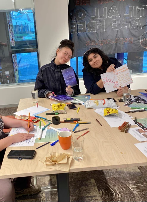 Image description: Picture of people writing cards at the Pōneke 2026 Matariki Holiday Card Drive. 