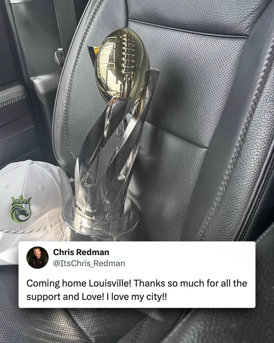 A football trophy sitting on a car seat next to a white cap with a dragon emblem. The mood is celebratory with a sense of local pride.