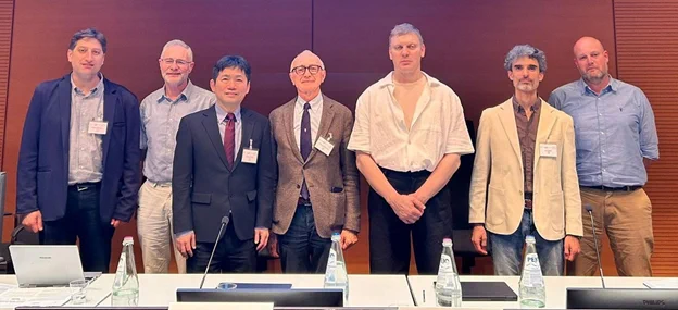 A group of men are standing behind a table before delivering a workshop to participants