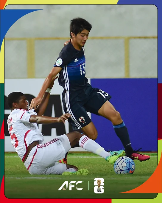 A dynamic scene from a soccer match featuring a player in blue tackling a player in white. The game appears competitive and engaging.
