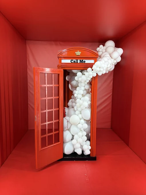 Eine britische Telefonzelle mit weißen Luftballons als Kunstinstallation