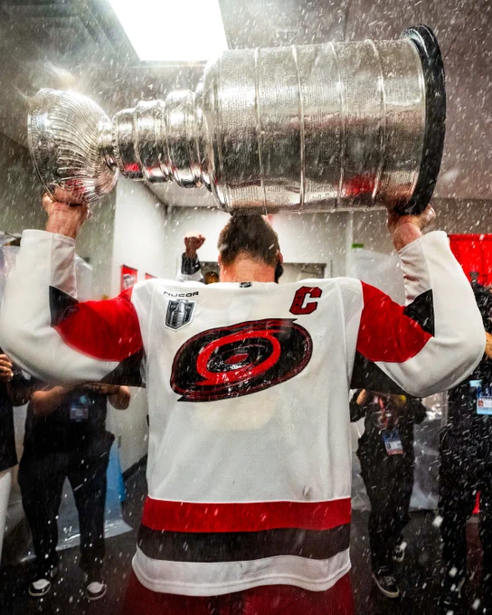 Photo of Jordan Staal in a Carolina Hurricanes uniform lifting the Stanley Cup in the locker room