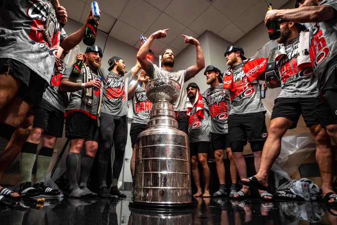Photo of Jordan Staal in front of the Stanley Cup celebrating with his teammates in the locker room