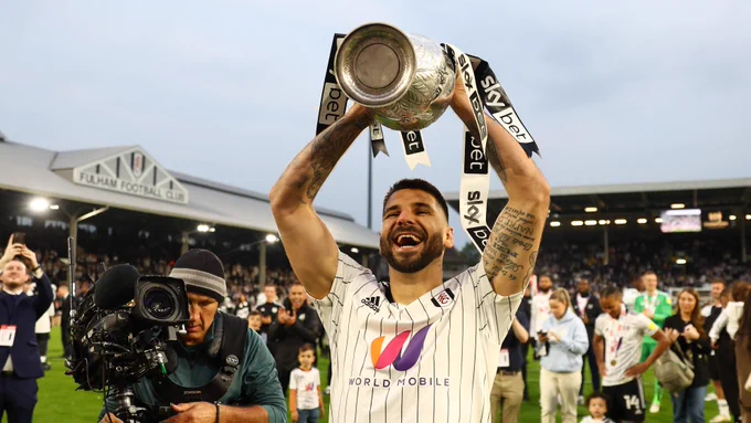 Aleksandar Mitrović lifts the Championship trophy aloft on the pitch at Craven Cottage in May 2022.